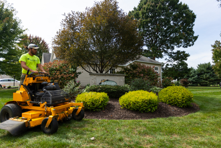 A professional landscaper mows a large, well-kept lawn.