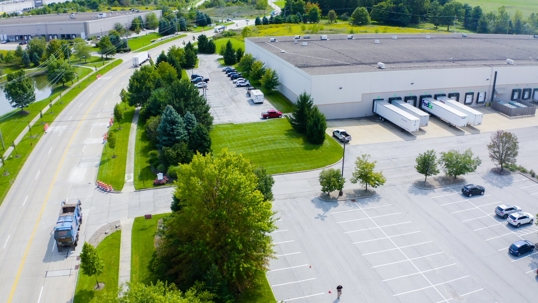 Aerial view of a well-maintained industrial park featuring a large warehouse with active loading docks.