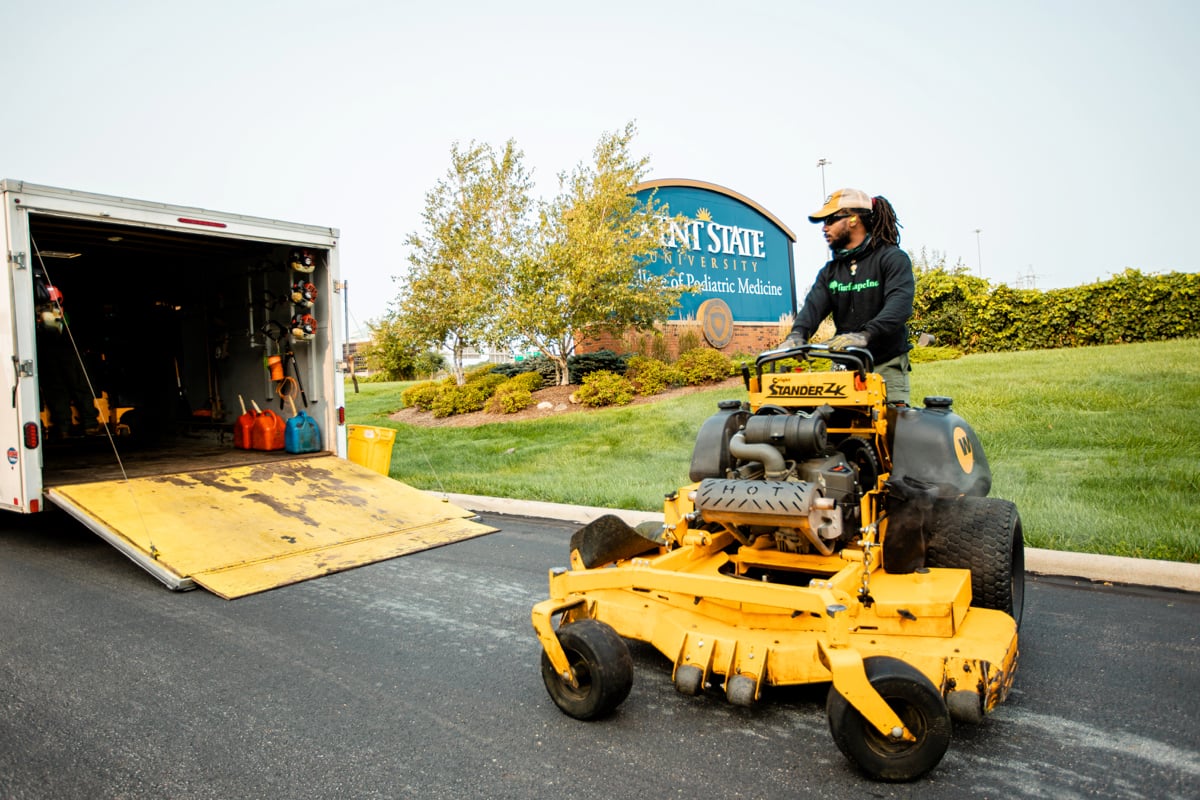 commercial landscape maintenance team unloads ride on mower