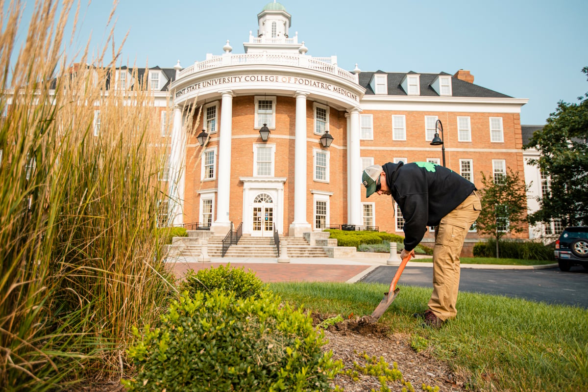 commercial landscape maintenance team edges landscape bed with edging shovel