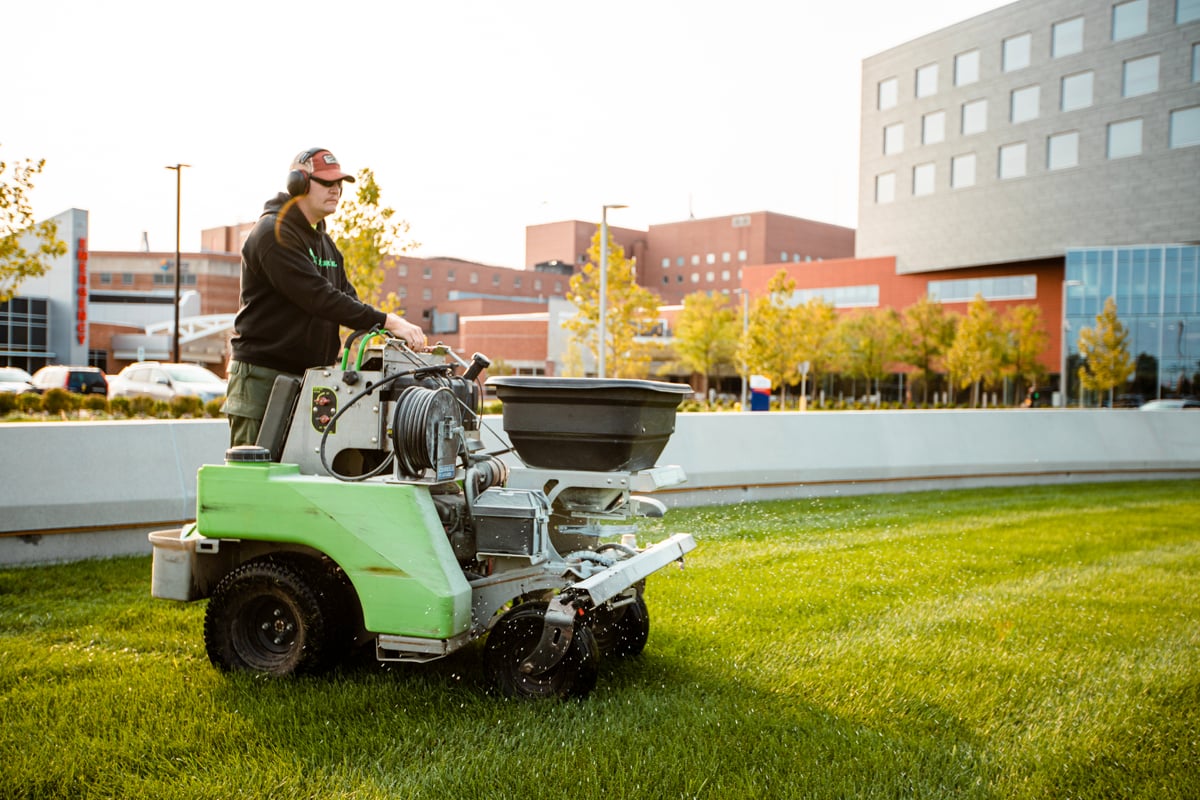 lawn care expert fertilizes grass at commercial property