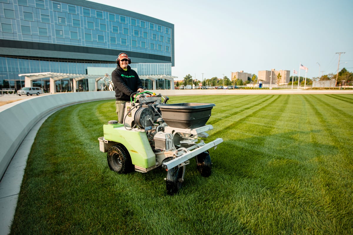 commercial lawn care team fertilizes grass