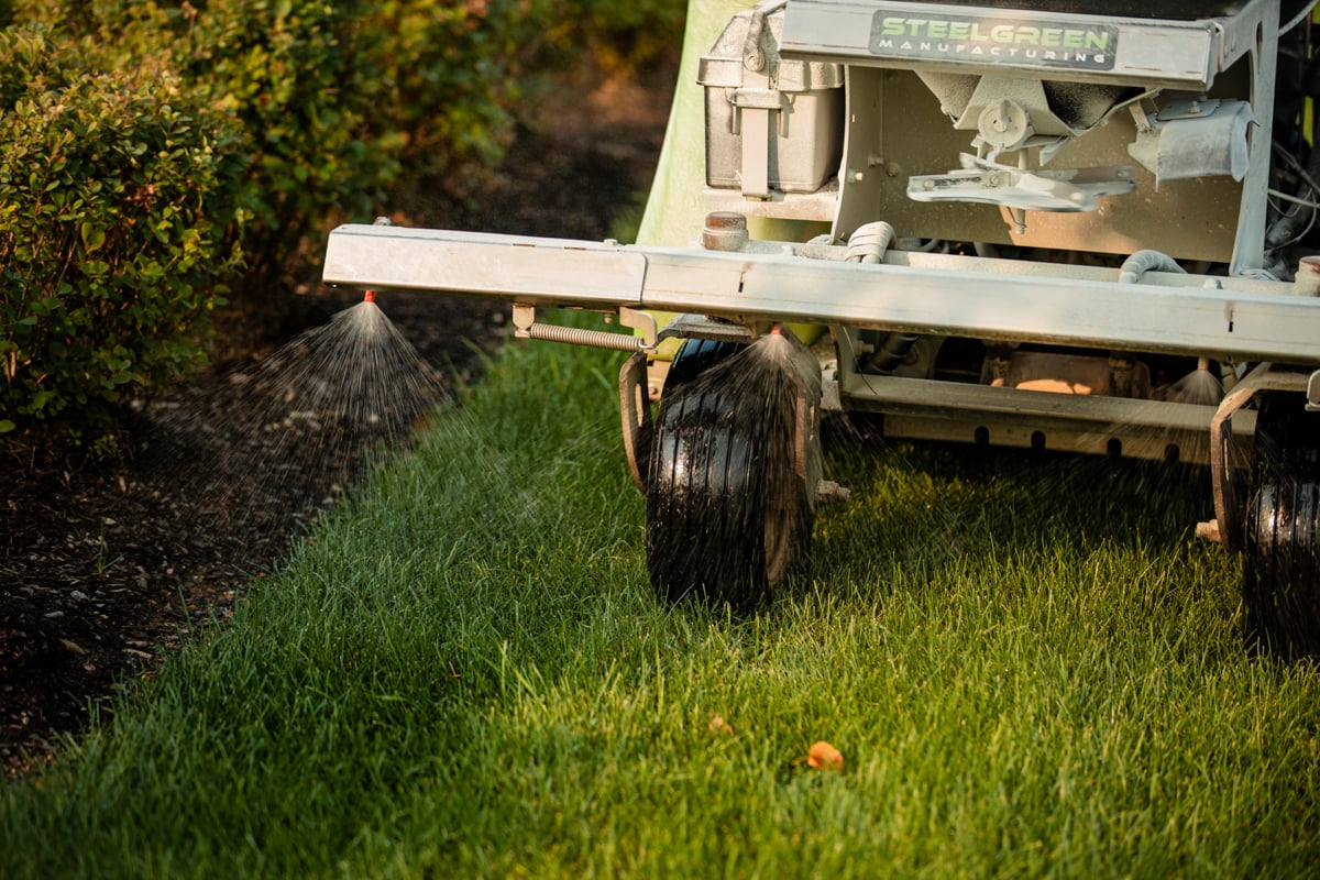 lawn care technician putting down liquid fertilizer on grass