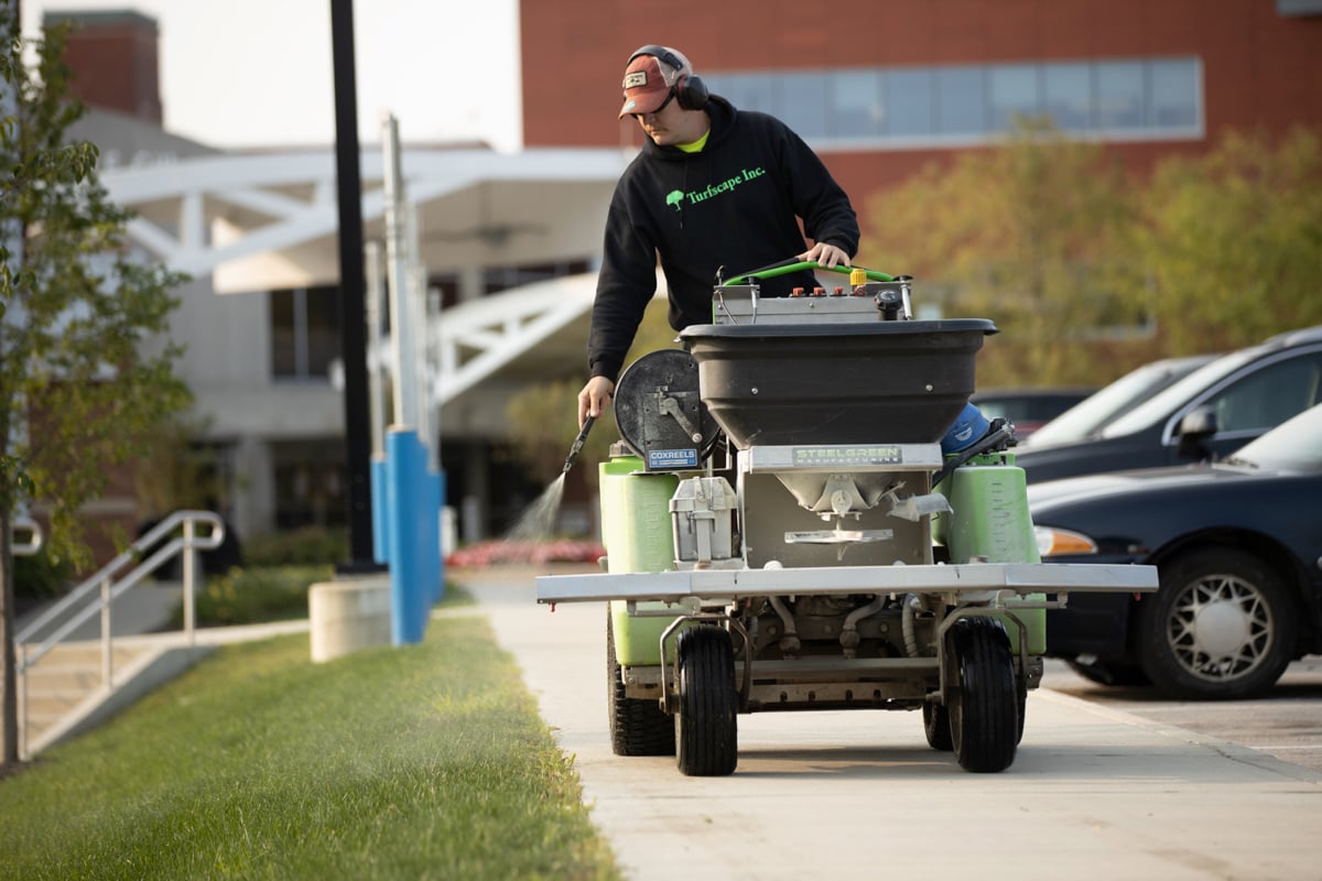 landscape expert sprays near edge of grass