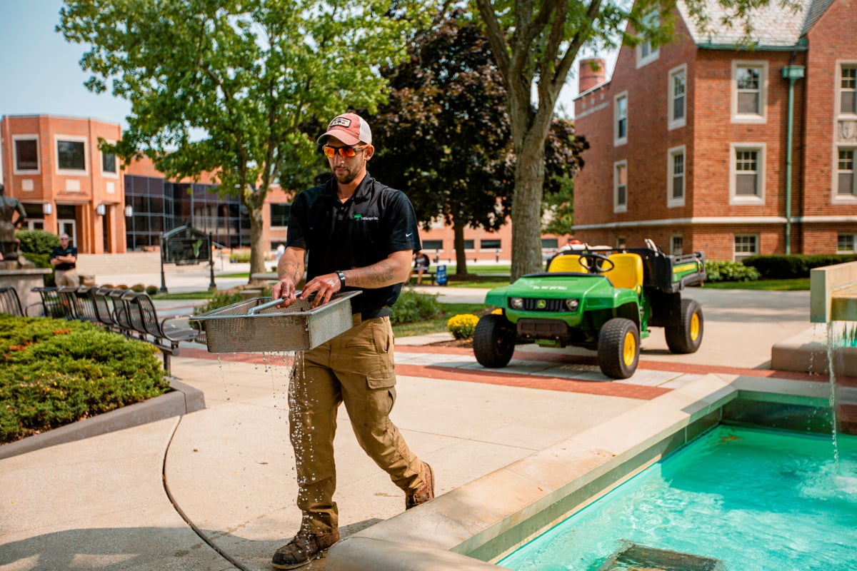 landscape professional cleans water feature