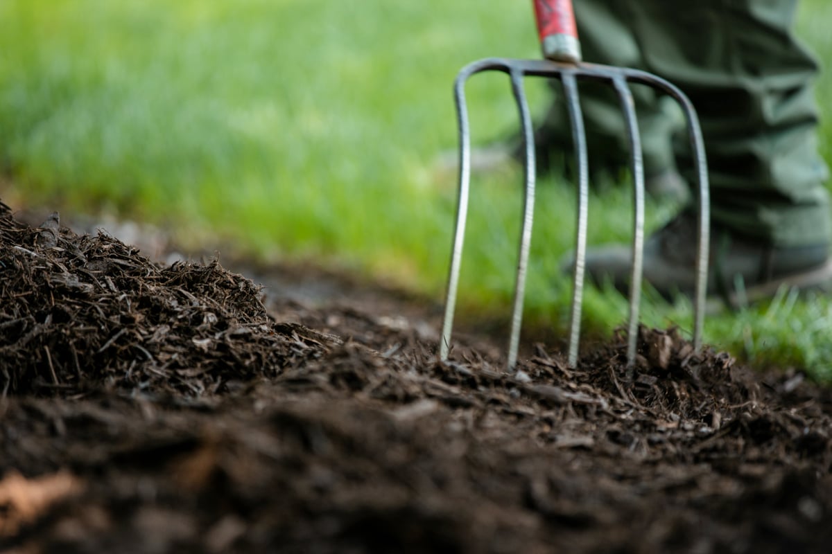 spreading out mulch in garden bed