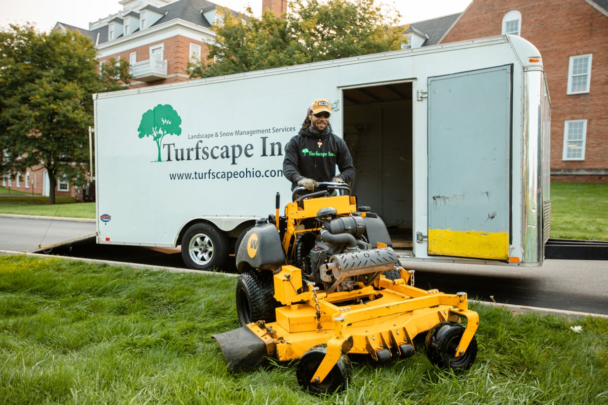 Commercial landscaping crew unloading mower