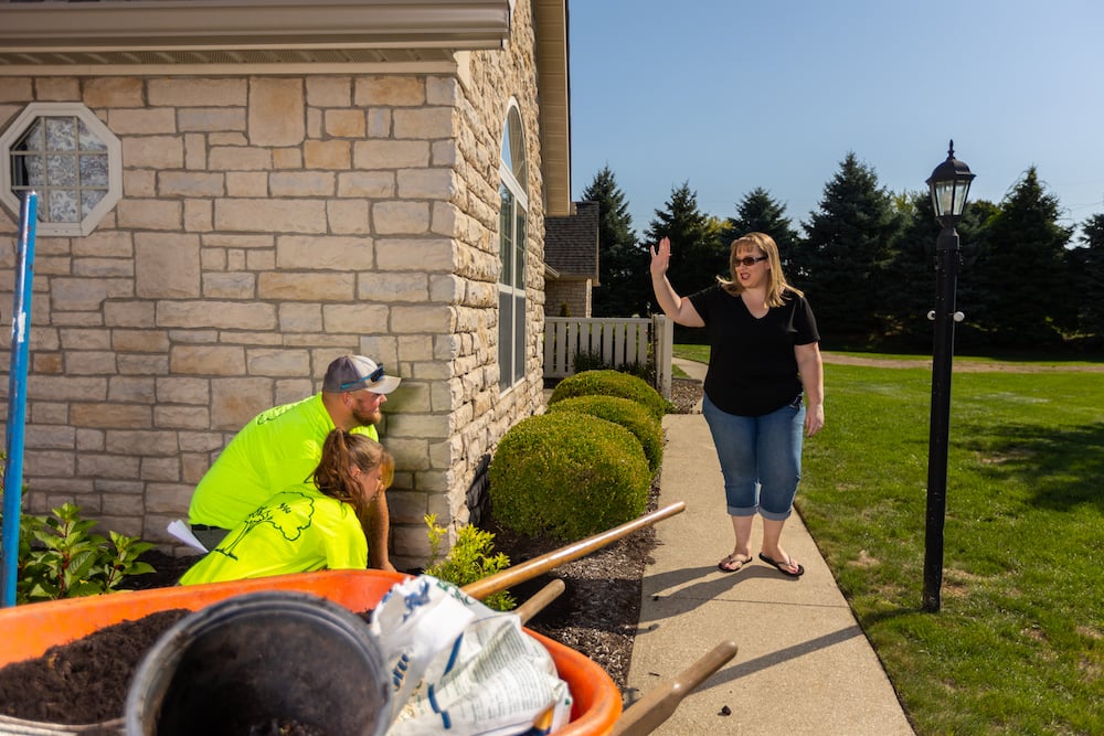 landscape crew planting plants with customer waving 