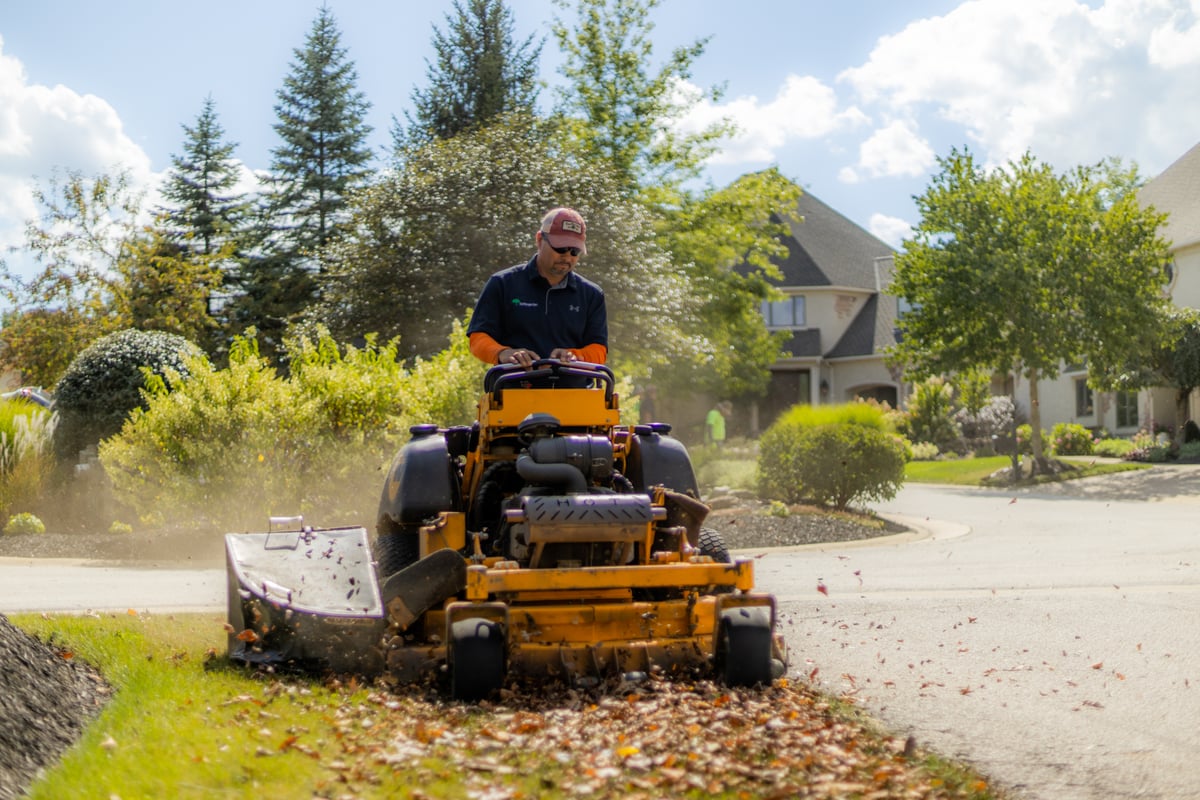 commercial landscape maintenance Crew bagging leaves with riding mower
