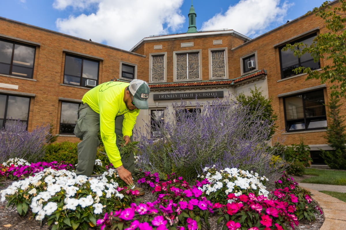 landscape maintenance team weeds beds at school