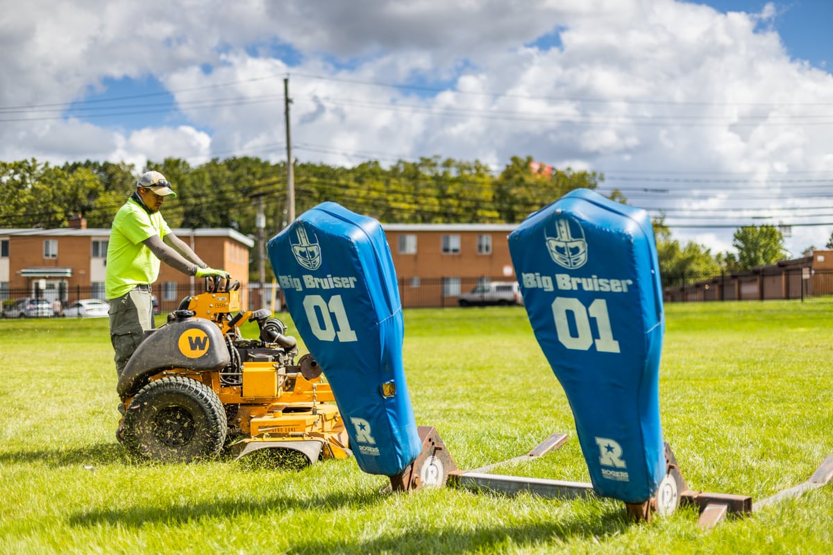 landscape maintenance team mowing football field