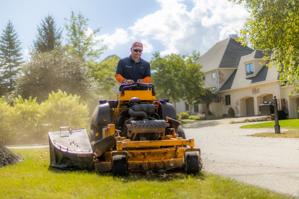 landscape maintenance team mows lawn near homes