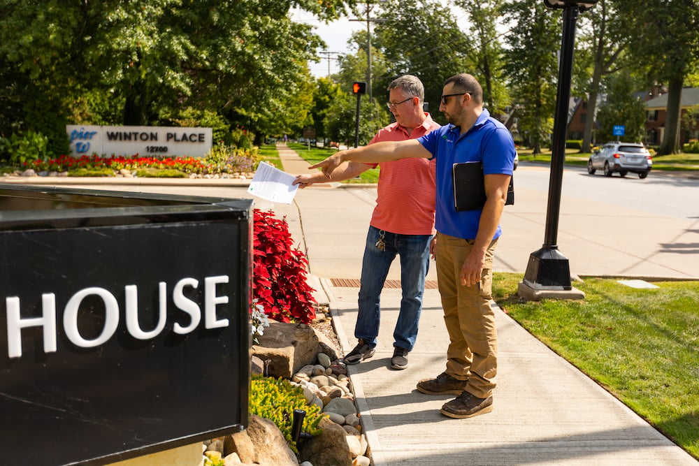 customer with account manager looking at flower beds and entry sign