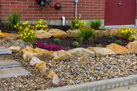 landscape beds with large rocks along paver step walkway