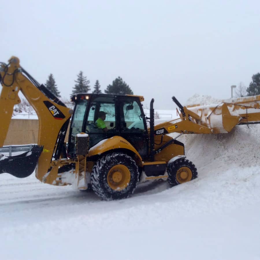 equipment pushes snow into snow pile