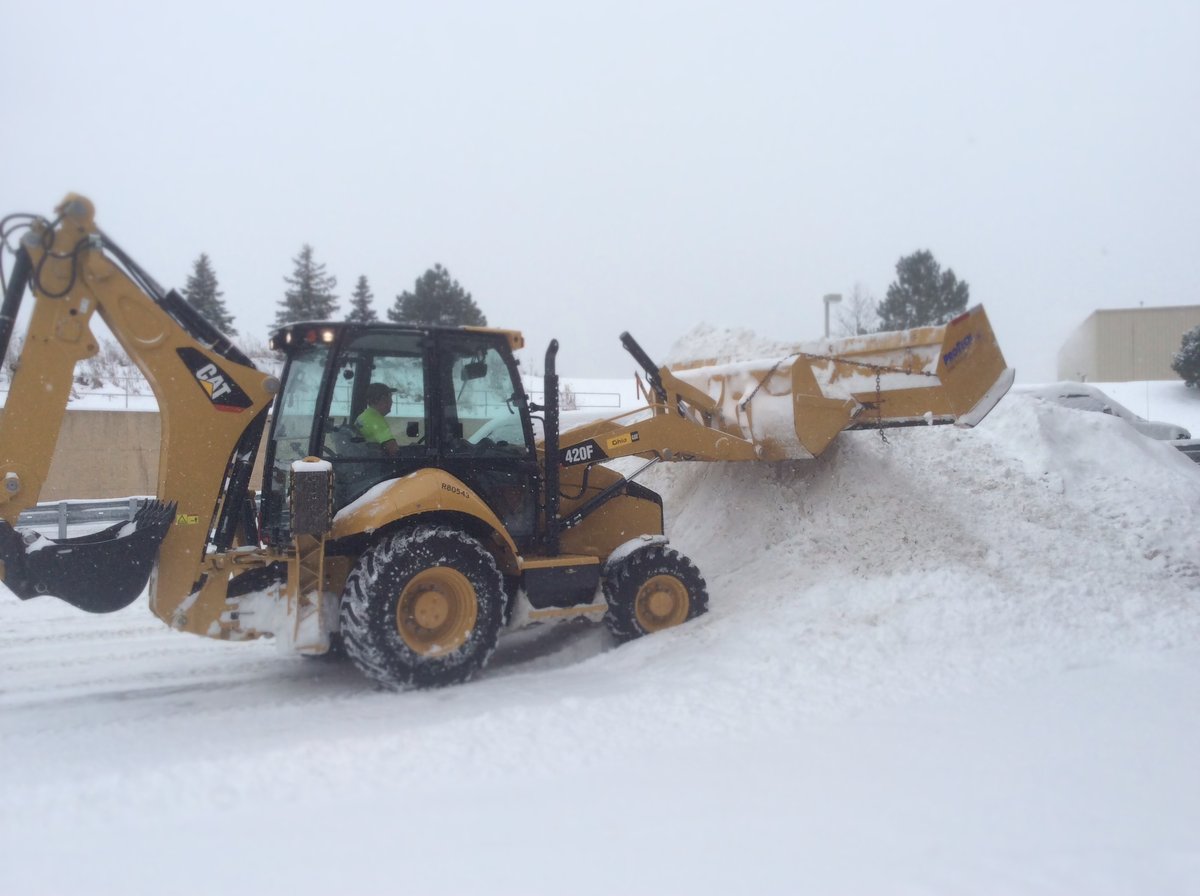 snow removal equipment piles snow in commercial parking lot