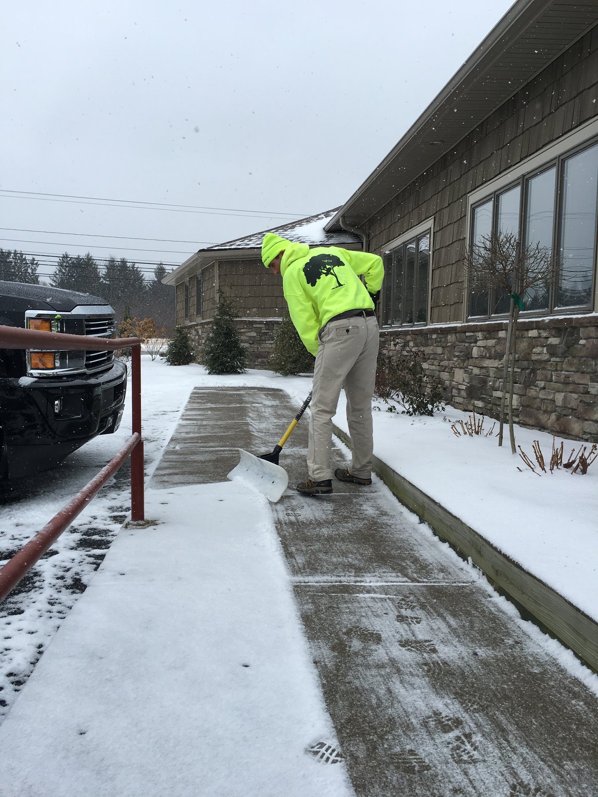 team member shovels snow at commercial building