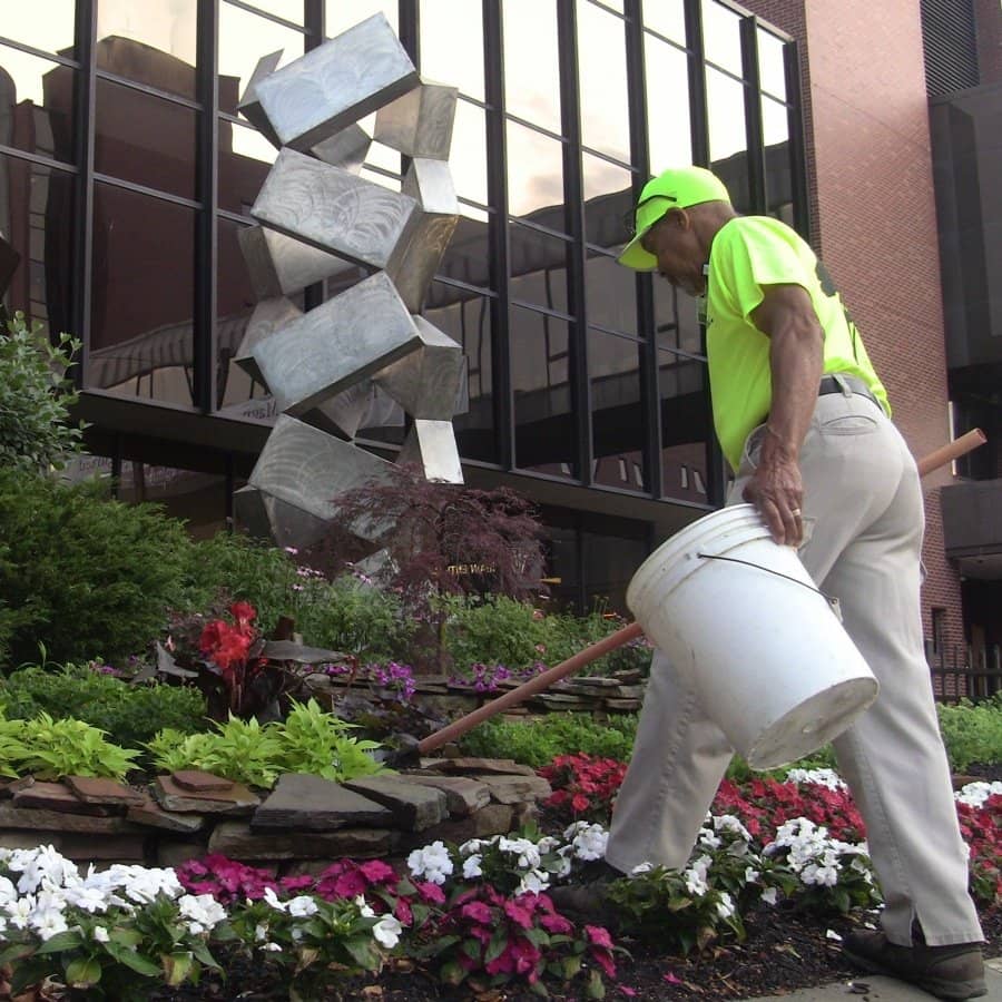 landscape maintenance crew picking up trash and debris out of landscaping beds