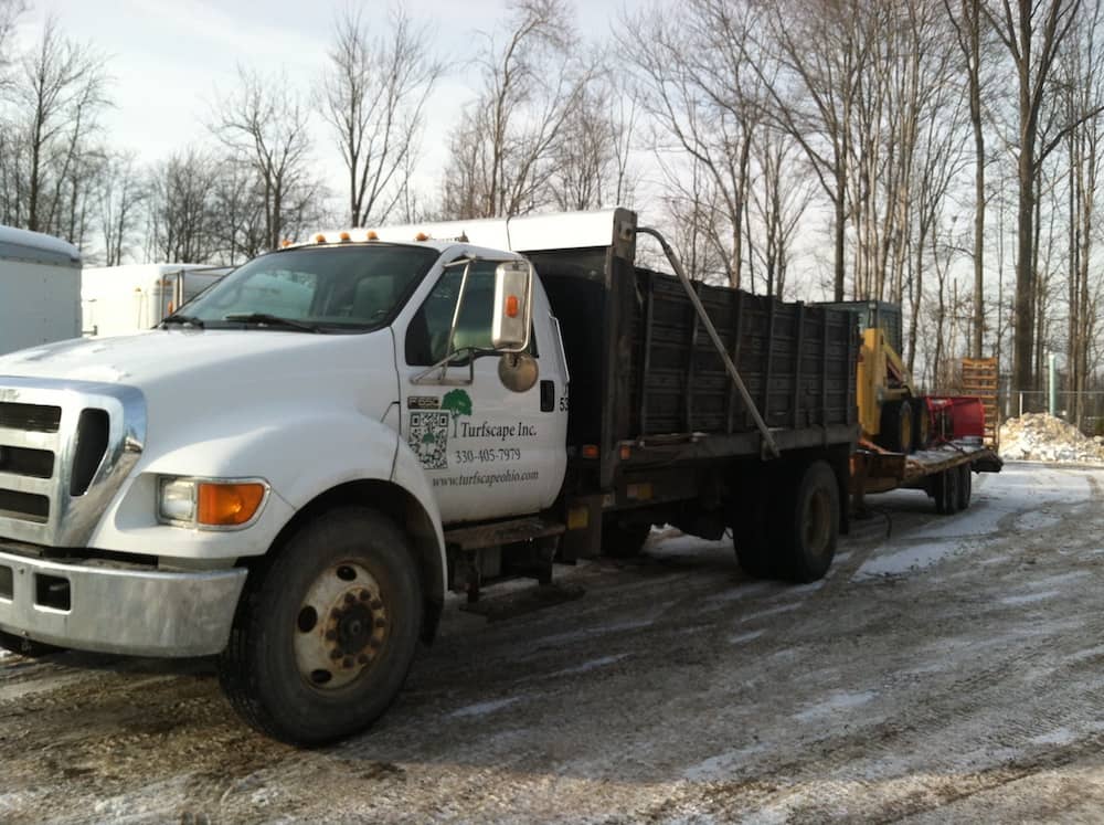 truck pulls trailer with skid loader