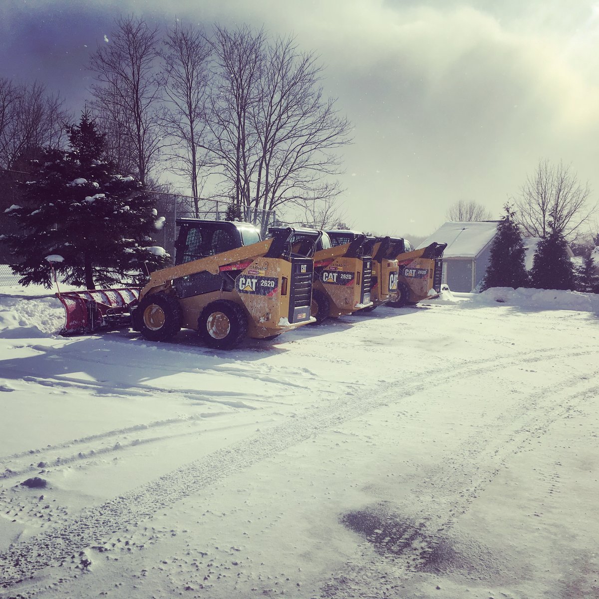 skid loaders parked in snowy parking lot