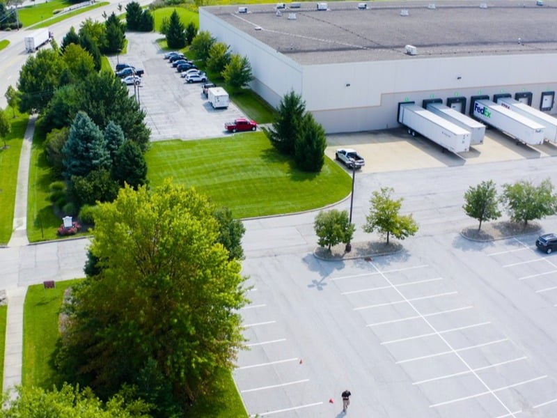 Aerial commercial warehouse parking lot landscape lawn trees